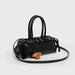 Black handbag with a small brown dog toy on a light gray background