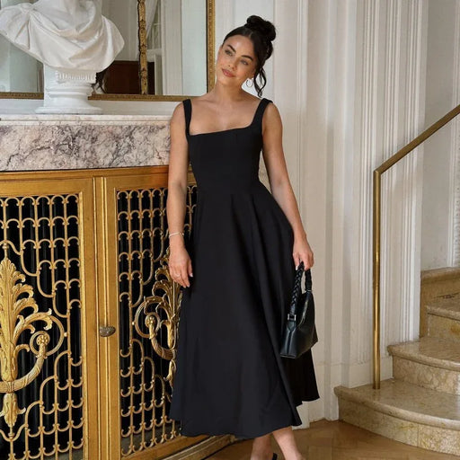 Woman in a black dress standing in an elegant interior setting with marble and gold accents.
