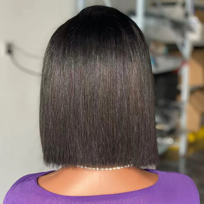 Person with a stylish haircut wearing a purple top in an indoor setting.