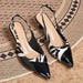 A pair of pointed-toe slingback heels with a glossy black and white zebra-print pattern, displayed on a textured woven rug.