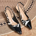 A pair of pointed-toe slingback heels with a glossy black and white zebra-print pattern, displayed on a textured woven rug.