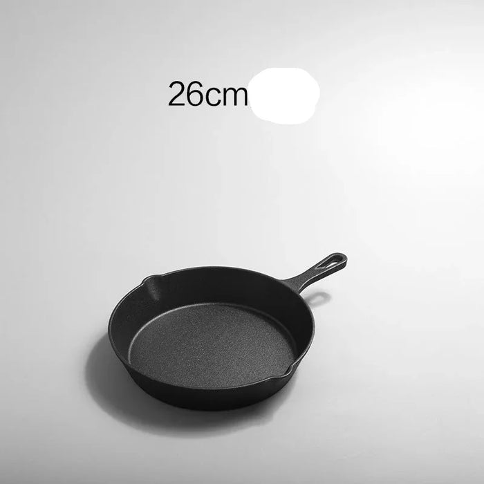Black frying pan with handle on a light gray background