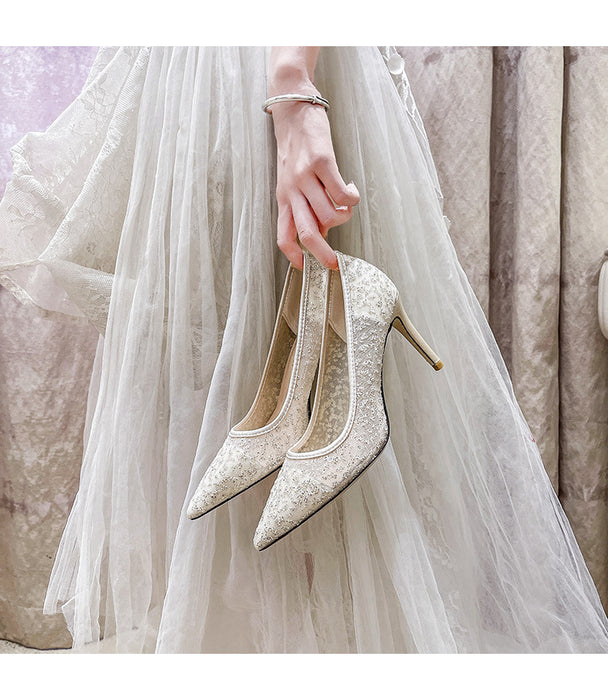 Bridal shoes held by a person wearing a white wedding dress.