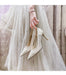 Bridal shoes held by a person wearing a white wedding dress.