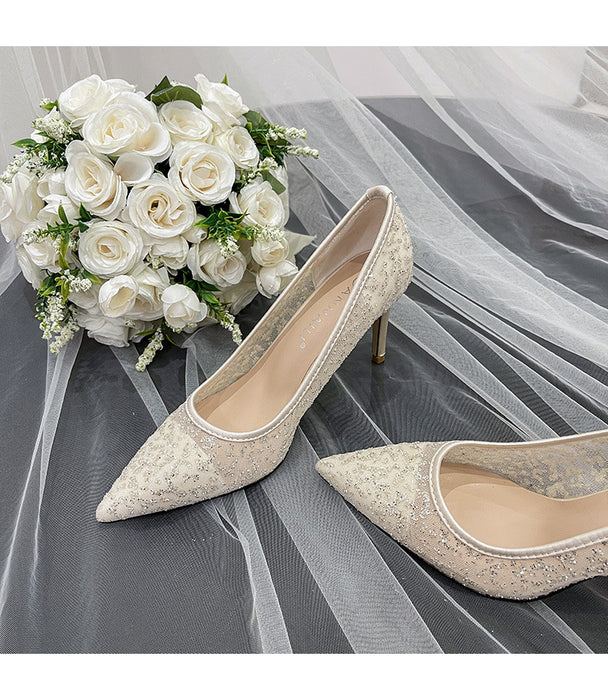 Pair of wedding shoes with a bouquet of white roses on a gray fabric background