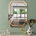 Gold-framed mirror on a green wall with decorative items below.