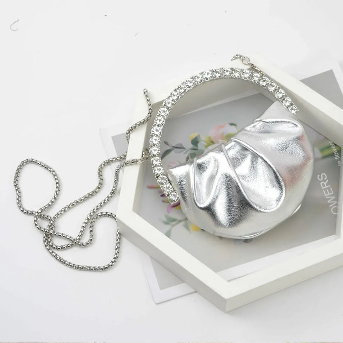 Silver clutch bag with a chain on a white surface