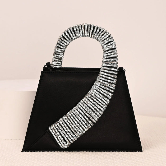 Black handbag with silver beaded handle on a light pink background