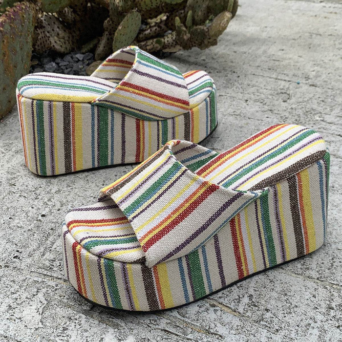 Colorful striped wedge sandals on a textured surface
