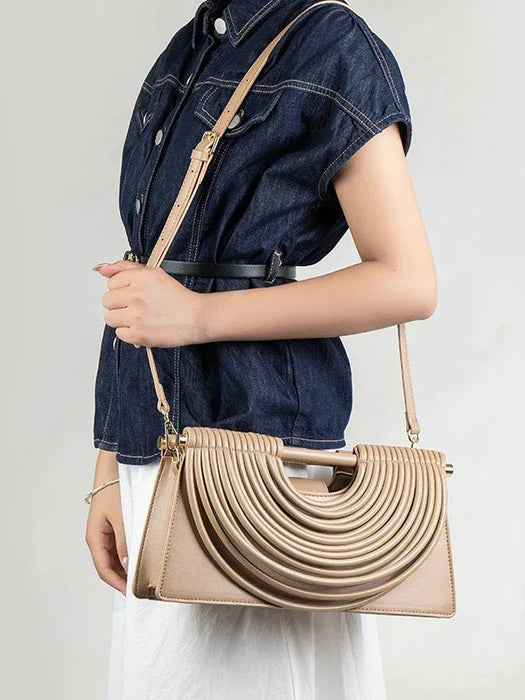Person holding a beige handbag with a plain background
