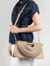 Person holding a beige handbag with a plain background