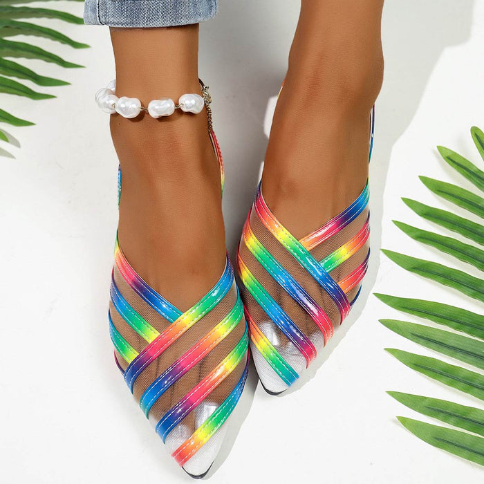 Multicolored strappy shoes worn with a white background and green leaves.