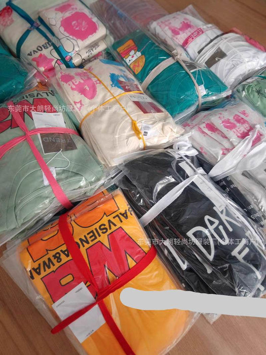 Stack of folded clothes with visible brand labels on a wooden surface