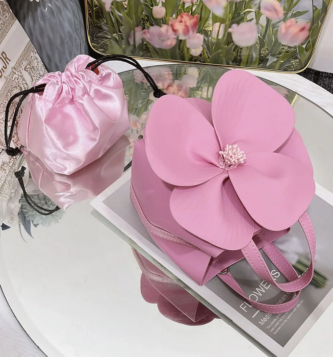 Pink flower-shaped handbag with a smaller pink pouch on a magazine