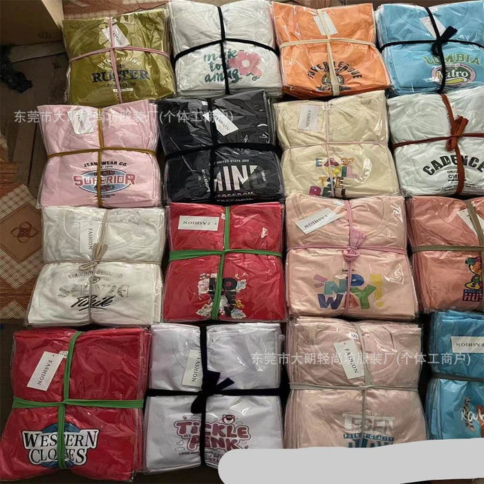 Collection of folded shirts with various designs and colors on a patterned surface.