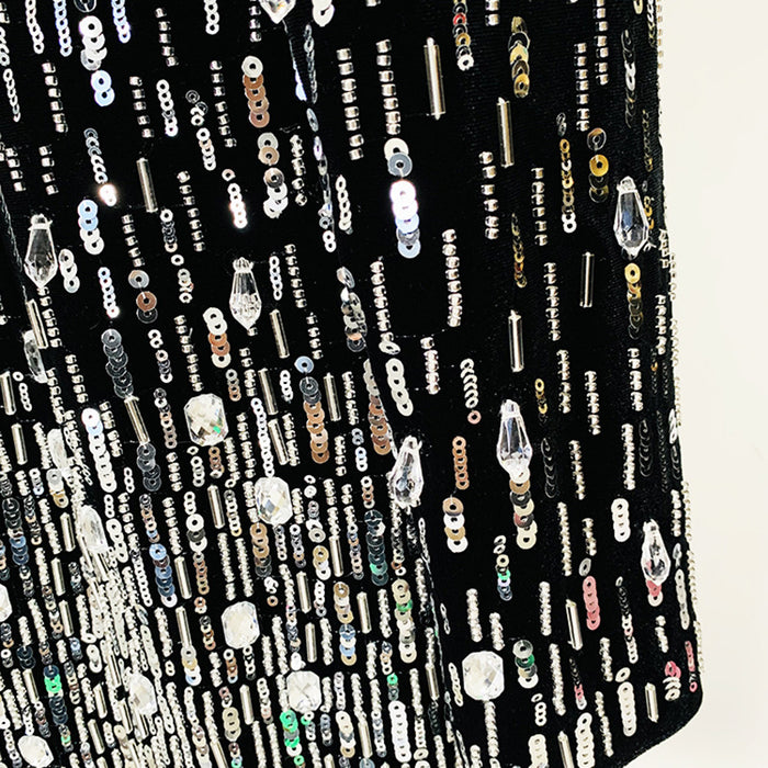 Close-up of a black fabric with various beads and sequins on a white background