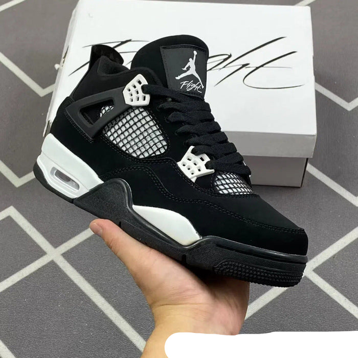 Black and white sneaker held in hand with Jordan box in the background