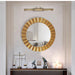 Gold circular mirror on a wall with decorative items below