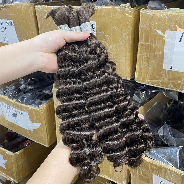 Person holding a bundle of curly hair extensions with boxes in the background