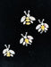 Four bee-shaped pins with yellow centers and clear gemstones on a black background