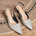 A pair of pointed-toe slingback pumps in a textured metallic silver finish, displayed on a woven rug.