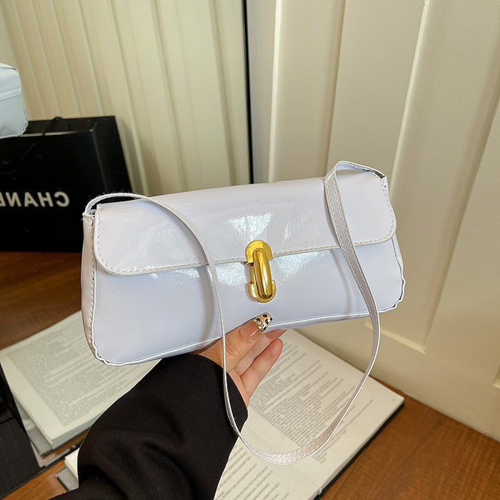 White handbag with gold clasp held by a person, with a blurred background