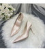 Pair of pink high-heeled shoes on a white fur surface with a bouquet of white roses in the background.