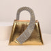 Gold handbag with a sparkling handle on a beige background