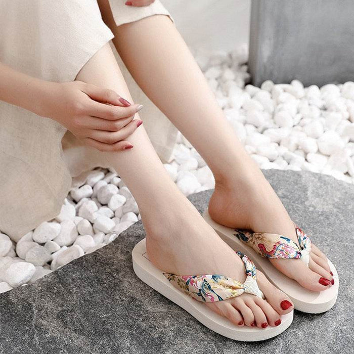 Person wearing floral sandals on a stone surface with pebbles in the background