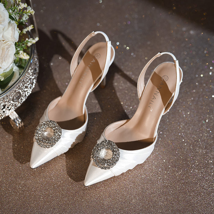 White high-heeled shoes with decorative brooches on a glittery surface.