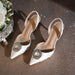 White high-heeled shoes with decorative brooches on a glittery surface.