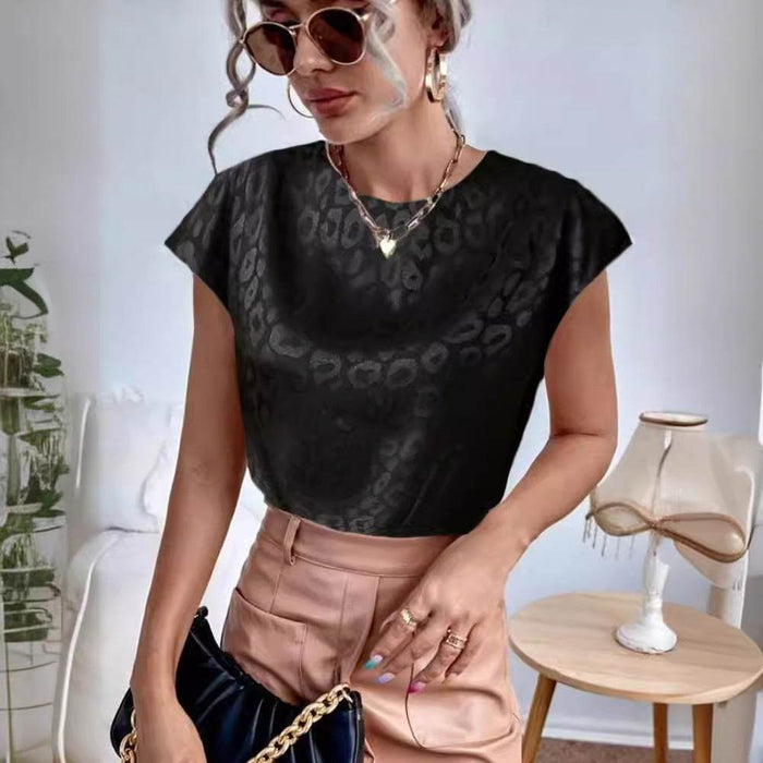 Woman wearing a black patterned top and beige pants in a room with a table and decorative items.