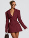 Woman wearing a burgundy blazer dress against a plain background