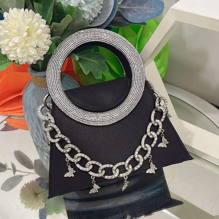 Silver chain necklace with circular pendant on a black stand against a floral background