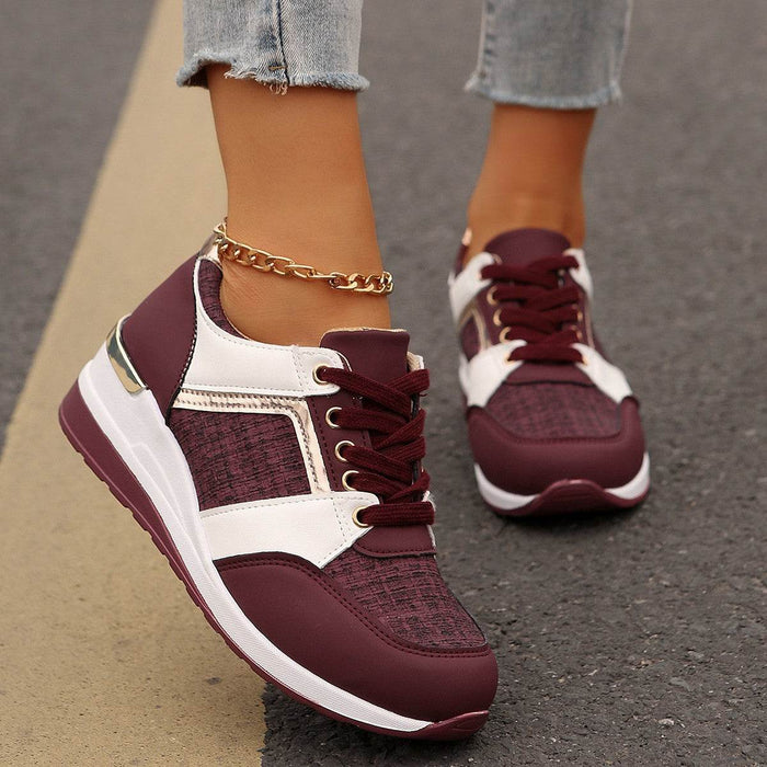 Maroon and white sneakers worn with light blue jeans on a pavement background
