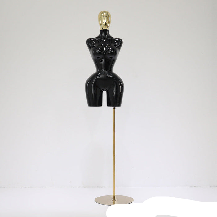 Black mannequin torso on a gold stand against a white background