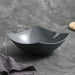 Black ceramic bowl with measurements on a gray surface