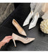 Beige and white high-heeled shoes on a dark floor with a bouquet of flowers.