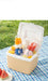 Portable juice maker with fruits on a checkered tablecloth outdoors