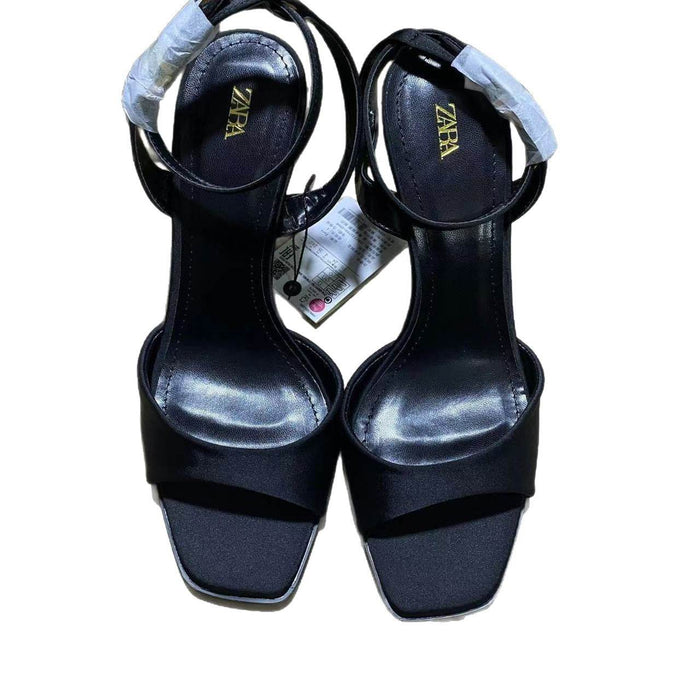 Black high-heeled sandals with 'Zara' branding on a white background