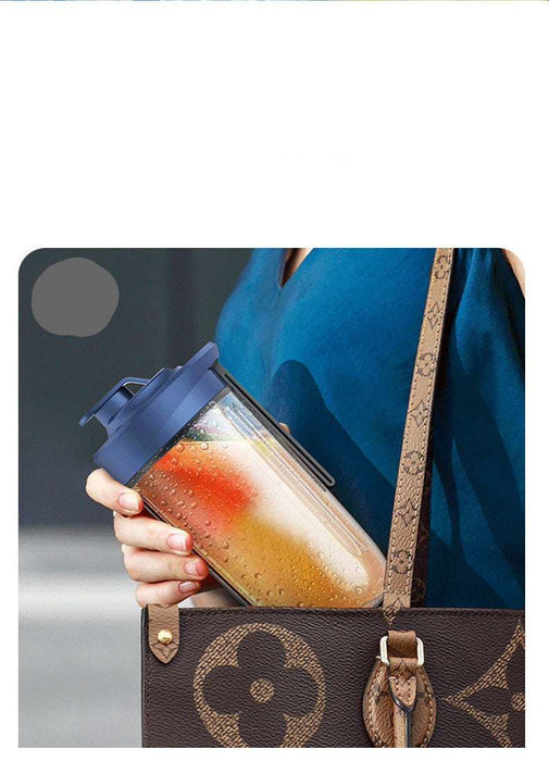 Person holding a portable juice container with a brown leather bag in the background