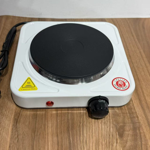 Portable electric hot plate on a wooden surface with warning labels.