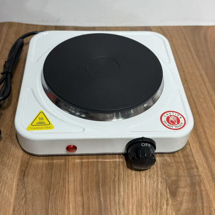 Portable electric hot plate on a wooden surface with warning labels.