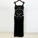 Black dress with floral embellishments on a wooden hanger against a white background