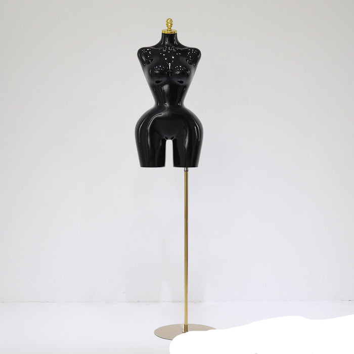 Black mannequin torso on a stand against a white background
