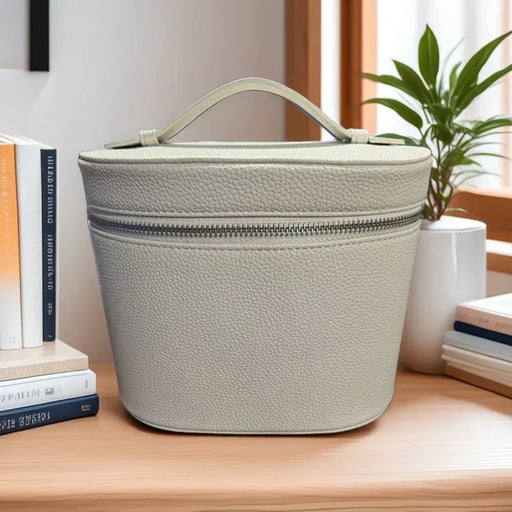Light gray textured storage bag on a wooden surface with books and a plant in the background