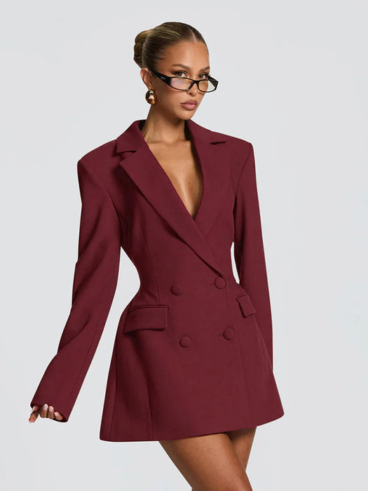 Woman wearing a burgundy blazer dress against a plain background
