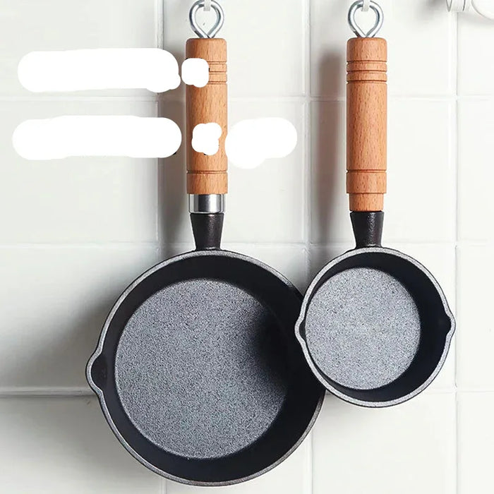 Two small frying pans with wooden handles hanging on a white tiled wall.