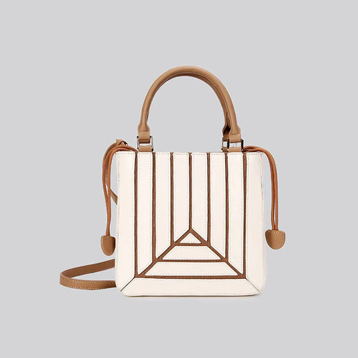 Handbag with geometric design and brown handle and strap on a light gray background