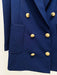 Close-up of a blue blazer with gold buttons on a light beige background